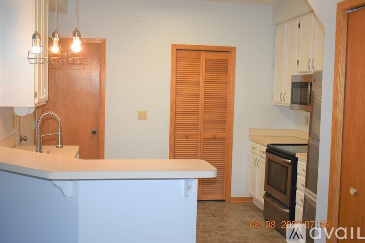 A kitchen with a white counter top and wooden cabinets.
