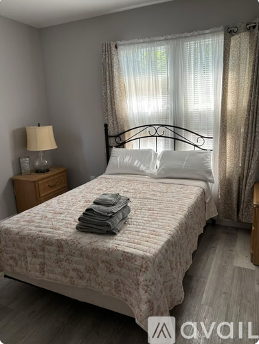 A bedroom with a bed, nightstand, and window.