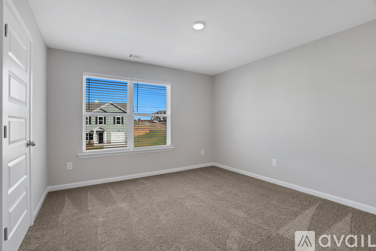 A room with a carpeted floor and a window showing a house and trees outside.