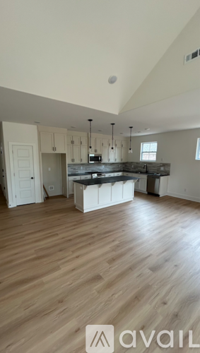 A spacious kitchen with wooden flooring and white cabinetry.
