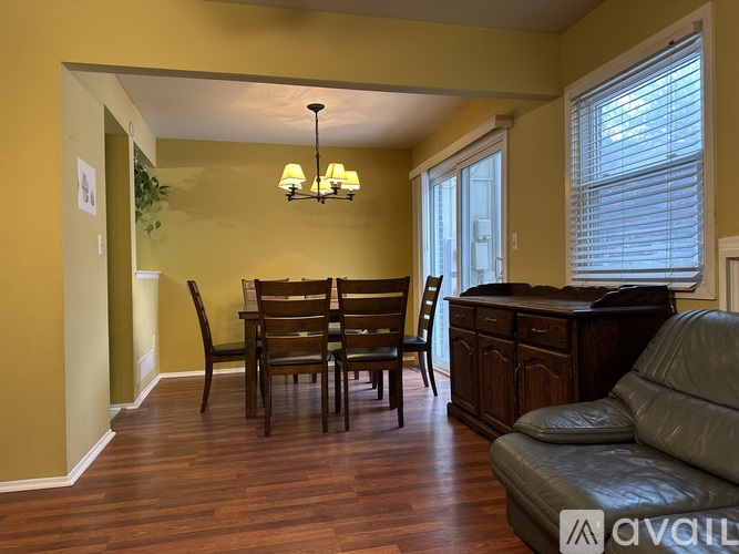 A living room with a brown leather couch and a wooden dining table.