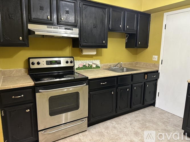 A kitchen with black cabinets and a stainless steel oven.