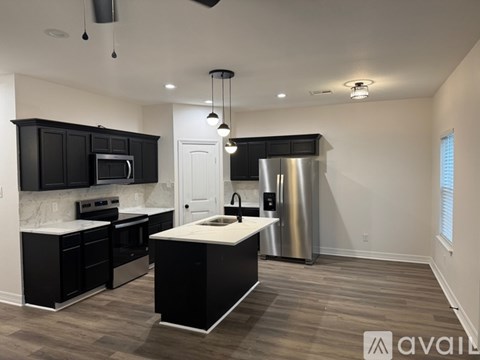 A modern kitchen with black cabinets and stainless steel appliances.