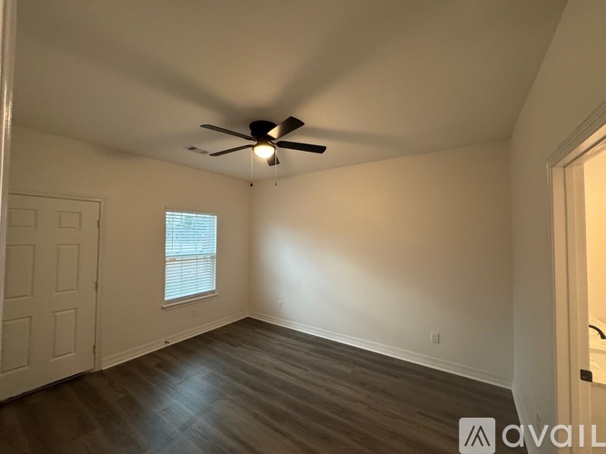 A room with a ceiling fan and wooden flooring.