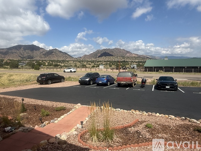 A parking lot with several cars and a mountain in the background.
