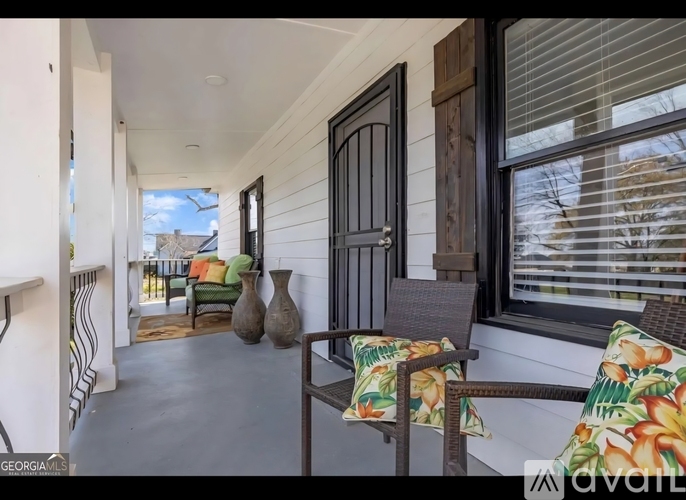 A balcony with a chair and a table with a vase on it.