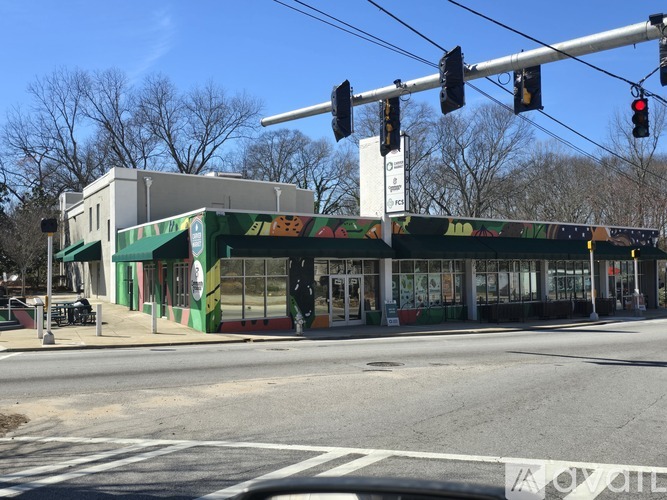 A street view with a traffic light and a building with a green and white facade.