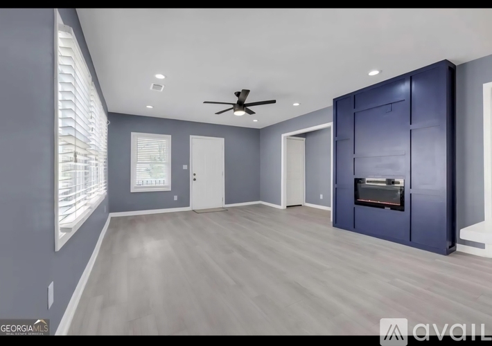 A spacious room with a ceiling fan and a fireplace.