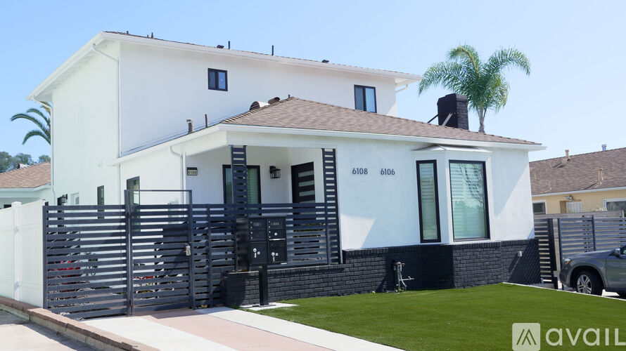 A modern house with a black gate and a palm tree in the background.