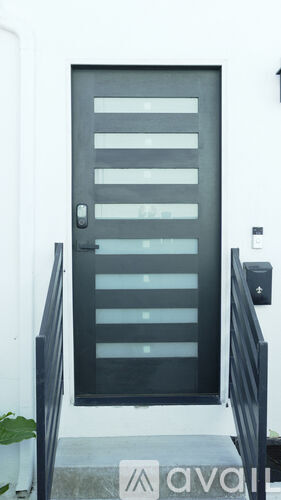A black door with a glass panel and a black railing on a white building.