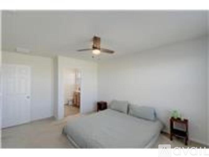 A bedroom with a bed, nightstand, and a ceiling fan.