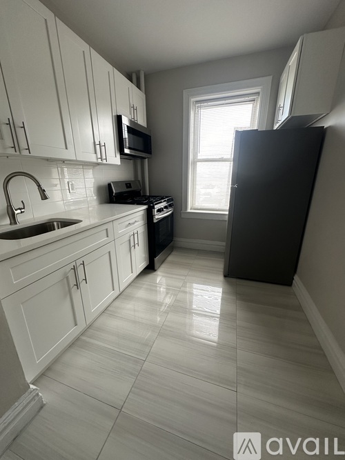 A kitchen with white cabinets and a black refrigerator.