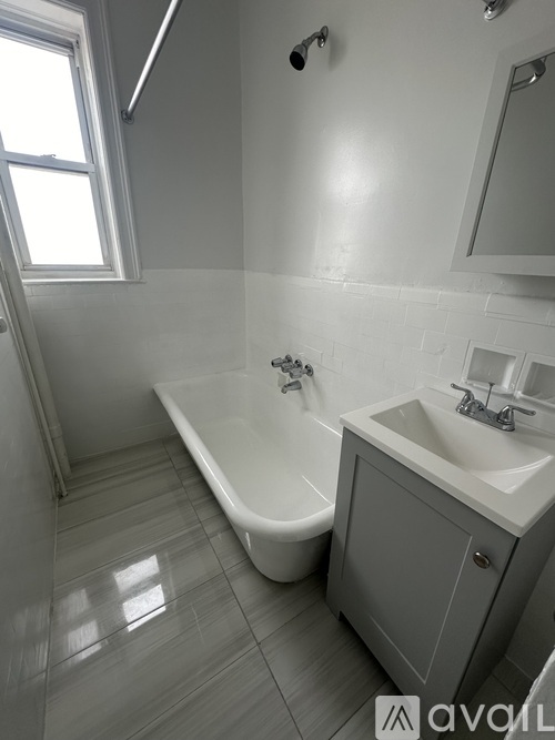 A white bathroom with a tub, sink and mirror.