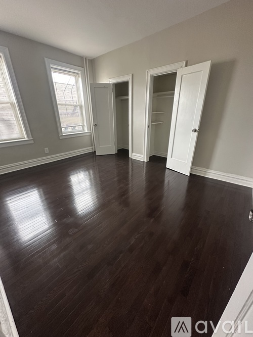 A room with wooden floors and three open doors.