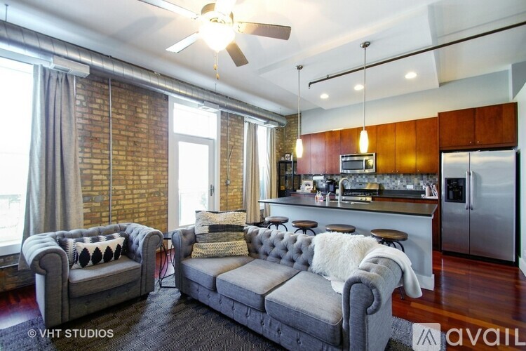 A living room with a grey couch and a kitchen area in the background.