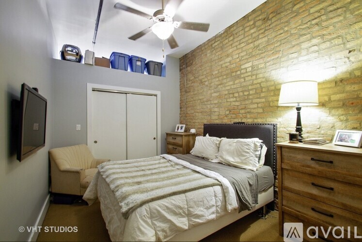 A bedroom with a brick wall and a bed with a white comforter.