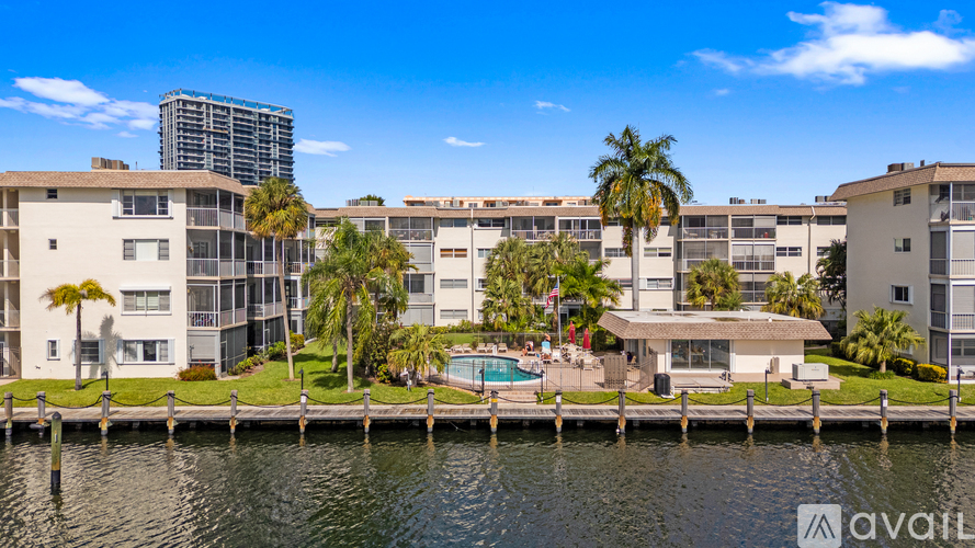 A row of modern apartment buildings with a pool and palm trees.
