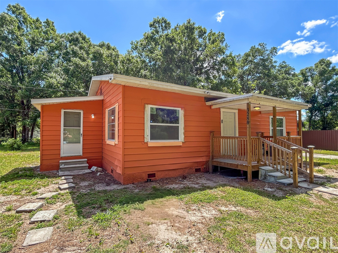 A small orange house with a porch and a white door.