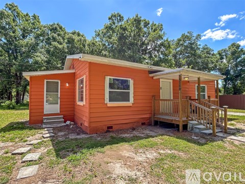 A small orange house with a porch and a white door.