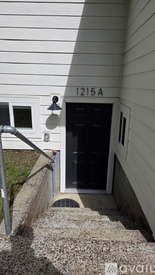A black door with a window above it and a number 1215A above the door.