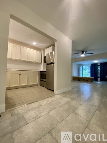 A kitchen with white cabinets and a refrigerator is shown.