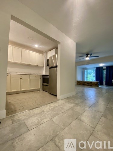 A kitchen with white cabinets and a refrigerator is shown.