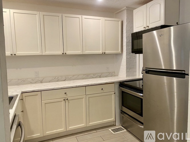 A kitchen with white cabinets and a stainless steel refrigerator.