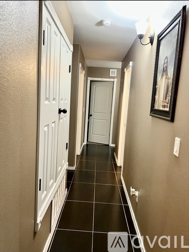 A hallway with a black tiled floor and white doors.