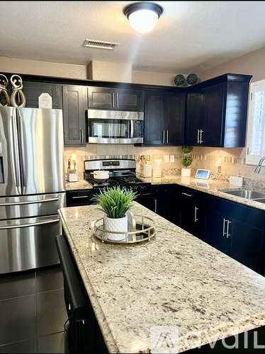 A kitchen with black cabinets and a granite countertop.