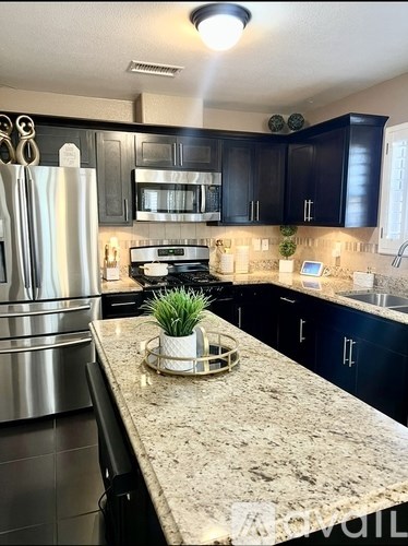 A kitchen with black cabinets and a granite countertop.