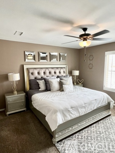A bedroom with a large bed and a ceiling fan.