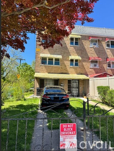 A car is parked in front of a building with a "Do Not Block Driveway" sign.