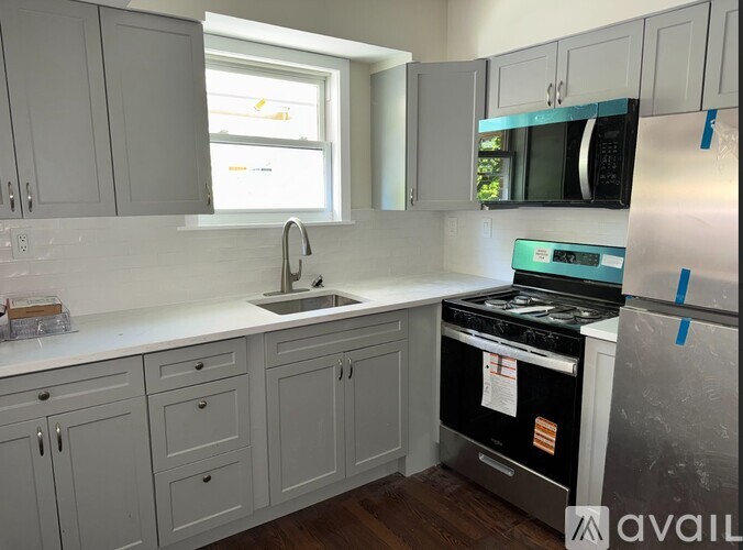A kitchen with a stove, sink, and cabinets.