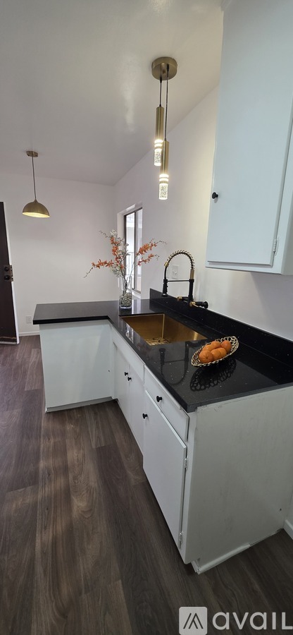 A kitchen with white cabinets and a black countertop.