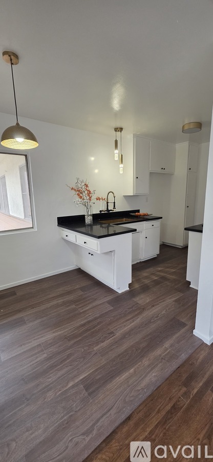 A kitchen with a black countertop and white cabinets.