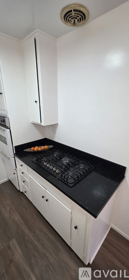 A kitchen with white cabinets and a black countertop.
