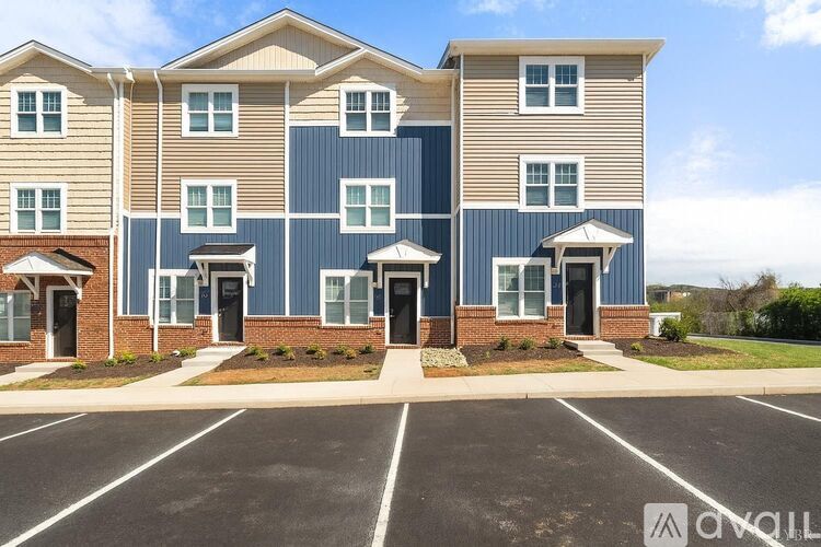 A row of townhouses with a parking lot in front.