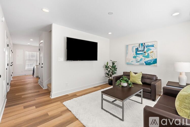 A living room with a brown couch and a painting on the wall.