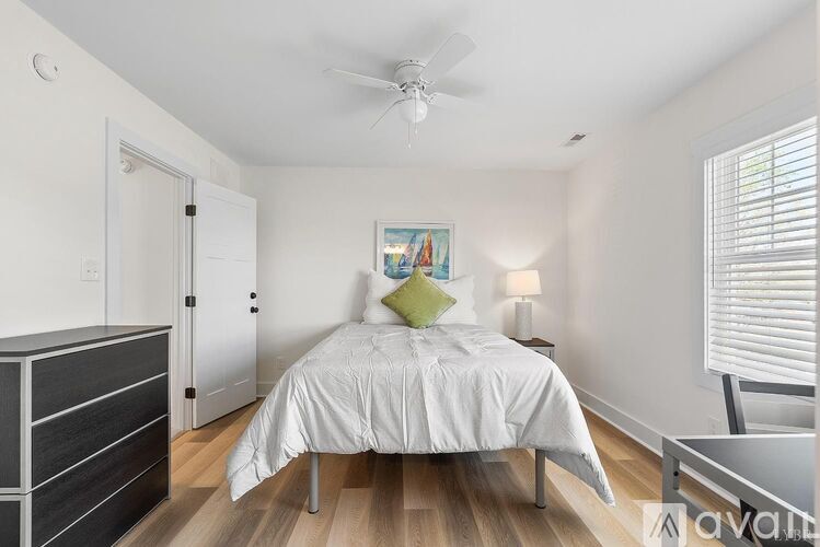 A bedroom with a bed, nightstand, and a painting on the wall.