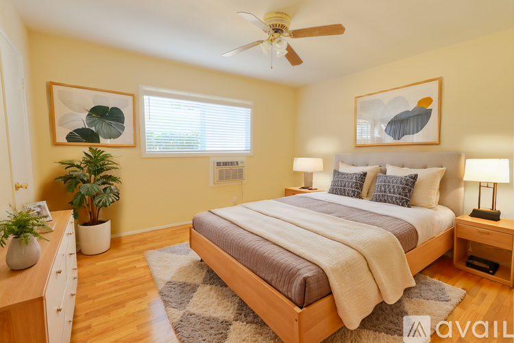 A bedroom with a large bed, a ceiling fan, and a rug on the floor.