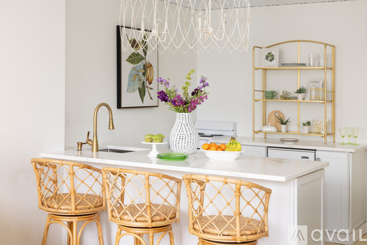 A kitchen with a white countertop and a sink with a gold faucet.