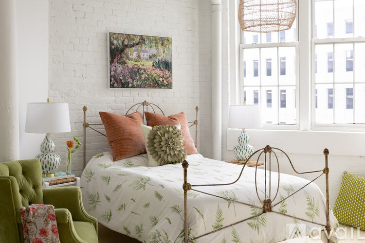 A bedroom with a white bed and a green chair.