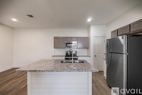 A kitchen with a granite countertop and stainless steel appliances.
