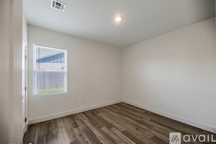 A room with wooden flooring and a window with blinds.