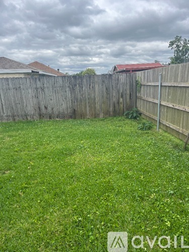 A backyard with a wooden fence and a grassy area.