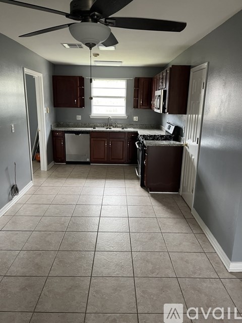 A kitchen with a tile floor and a ceiling fan.