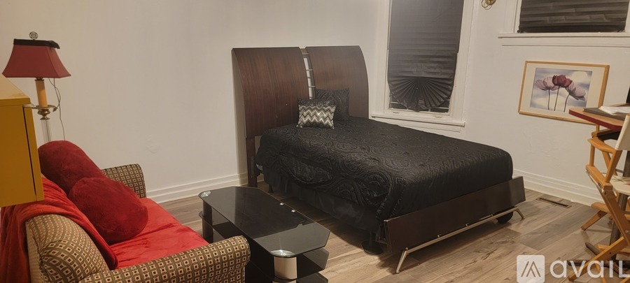 A bedroom with a black bed and a red chair.