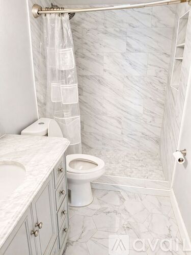 A white toilet in a bathroom with a marble tile floor.