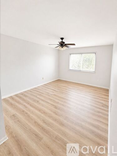 A room with wooden flooring and a ceiling fan.