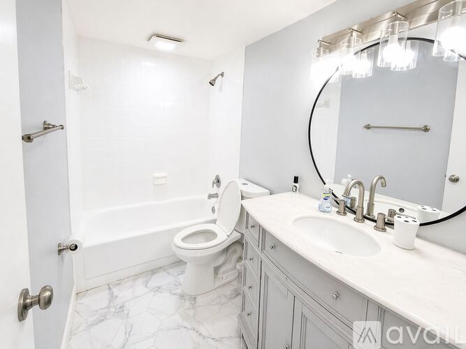 A white bathroom with a toilet, sink, and mirror.